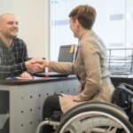 Kvinna i rullstol som skakar hand med man