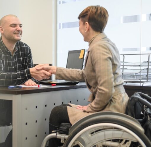 Kvinna i rullstol som skakar hand med man