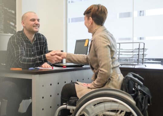 Kvinna i rullstol som skakar hand med man